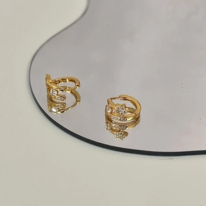 Detailed view of 18K gold star hoop earrings with micro-pave crystals on a mirror