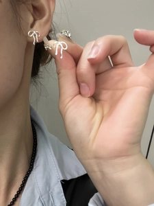 Close-up of sweet bow-shaped silver stud earrings showing on-ear wearing effect