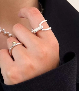 Gros plan de bagues minimalistes en argent 925 avec perle dorée sur une main