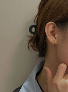 Detail view of a dainty gold bow stud earring worn by a model for a chic daily style