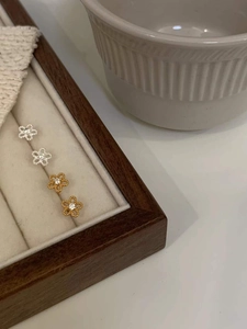 Close-up of small silver and gold sunflower stud earrings with cubic zirconia on velvet