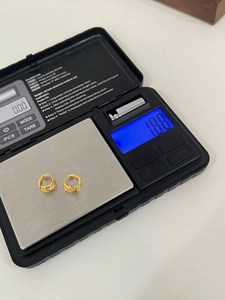 Macro view of sterling silver gold-plated hoop earrings weighing 1.88g on a digital scale