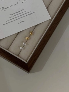Detailed view of minimalist gold and silver knot stud earrings on jewelry velvet display