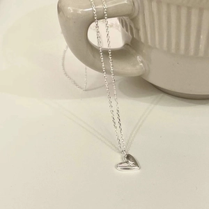 Detail der S925 Sterlingsilber Herzkette mit Sternengravur an einer Keramiktasse