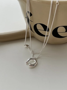 Macro view of silver horseshoe pendant necklace draped over a white ceramic mug