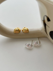 Détail macro de boucles d'oreilles nœuds torsadés dorées et argentées sur une tasse