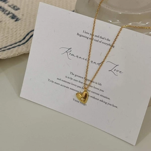 Detail einer minimalistischen goldenen Herzkette auf einer romantischen weißen Karte