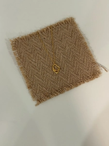 Detailaufnahme der ineinandergreifenden goldenen Herzanhänger an einer feinen Kette