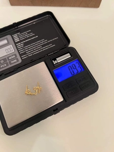 Detail shot showing the weight of 0.93g for these golden bow-knot style earrings