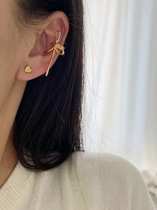 Détail d'un ensemble de bague d'oreille nœud doré et clou d'oreille cœur sur mannequin