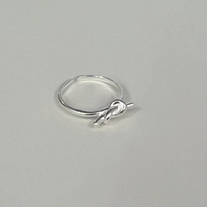 Détail macro d'une bague nœud en argent sterling S925 au design minimaliste poli