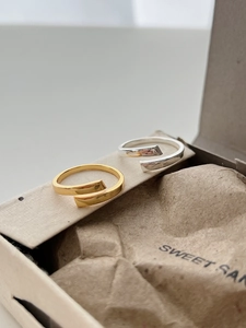 Detail of minimalist gold and silver intertwined open rings on eco-friendly packaging