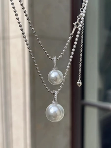 Detailed close-up of white pearl necklaces with shimmering pavé diamond heart charms