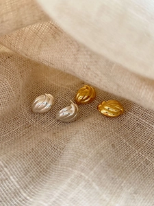 Gros plan sur des boucles d'oreilles torsadées dorées et argentées sur lin beige