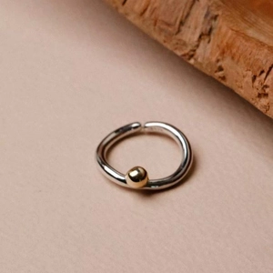 Bague minimaliste en argent 925 avec perle dorée contrastée sur fond naturel chaud