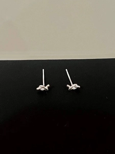 Macro detail of minimalist silver knot stud earrings in 925 sterling silver with polished finish