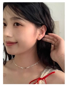 Close-up of model wearing tiny silver bow necklace and stud earrings set for women