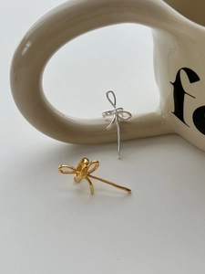 Détail montrant des boucles d'oreilles nœud élégantes en or et argent sur une tasse