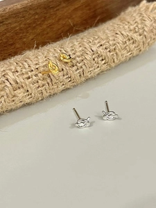 Close-up of minimalist gold and silver knot earrings on natural jute rope and smooth surface
