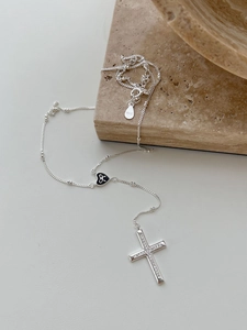 Macro shot of S925 sterling silver necklace featuring a diamond cross and black heart charm