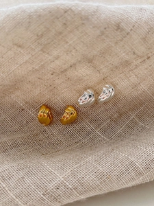 Gros plan de boucles d'oreilles nœuds torsadés en or et argent sur tissu en lin