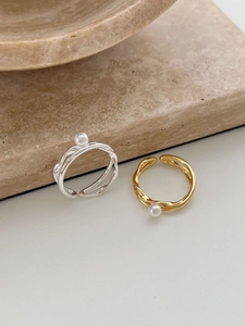 Detail of interlocking silver and gold rings with white pearls on a stone base