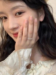 Close-up of 925 sterling silver sun flower earrings and bow ring worn by a model