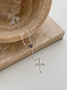 Detail of silver chain with black heart charm and sparkling zircon cross pendant