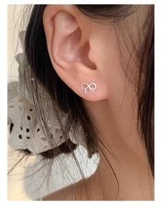 Close-up of mini 925 sterling silver bow stud earrings on a model's ear