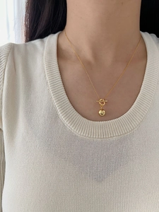 Detail of a minimalist gold S925 sterling silver ball pendant necklace with OT toggle clasp