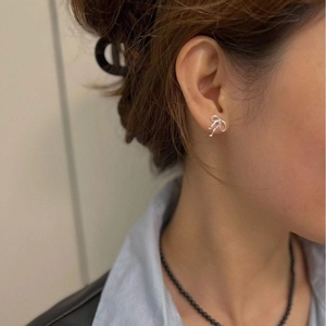 Elegant silver bow stud earrings with a ribbon twist design worn by a model