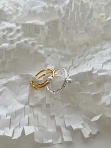 Close-up of gold and silver minimalist cross rings with white pearls on honeycomb paper