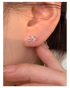 Close-up of mini S925 silver bow stud earrings worn on the ear, Korean minimalist style