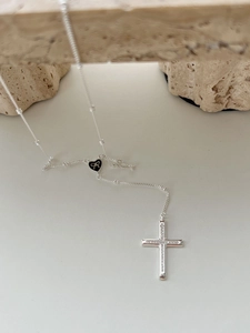 Detailed close-up of a silver beaded necklace with black heart and diamond cross pendant