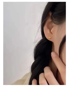 Close-up of minimalist gold-plated knot stud earring worn by a model for a chic look