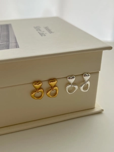 Detail of gold and silver layered hollow heart-shaped earrings on a notebook
