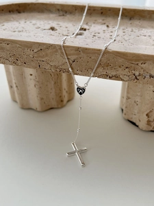 Detailed close-up of S925 sterling silver cross and heart pendant on stone