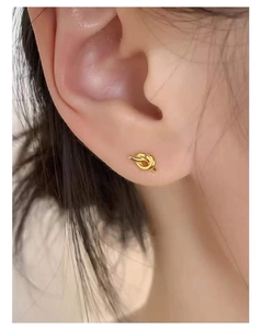 Close-up view of a minimalist golden knotted stud earring worn on the earlobe