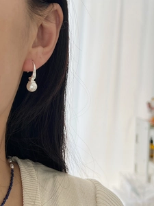 Close-up of elegant C-shaped pearl earrings with 925 silver hooks on female model