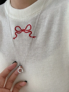 Macro shot of a silver horseshoe pendant necklace on a white knitted sweater