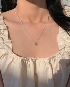 Detail of S925 silver heart planet pendant necklace worn on a model with elegant lighting