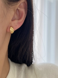 Gros plan de boucles d'oreilles créoles torsadées dorées portées par un mannequin