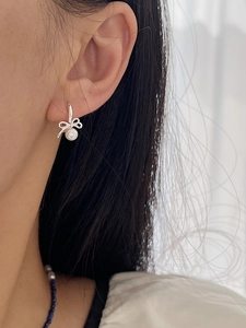 Close-up of 925 sterling silver bow earrings with round white pearl drop on model