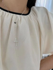 Detail of silver 925 cross necklace with black heart and bow pendant on model