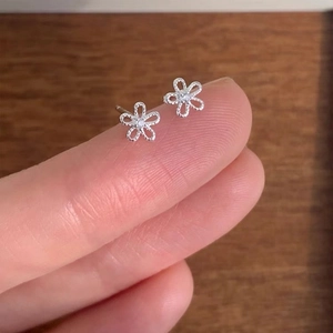 Delicate 925 sterling silver sun flower stud earrings with zircon held on a finger tip