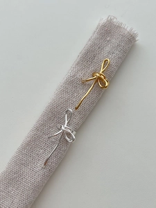 Détail macro du耳cuff en forme de nœud avec finitions en métal doré et argenté poli