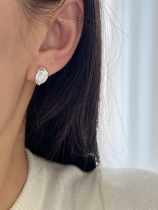 Gros plan de boucles d'oreilles nœuds multicouches en argent portées par un mannequin