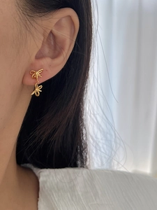 Detail of gold ribbon bow earrings on model showing delicate vintage Korean style