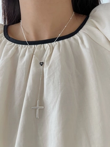 Macro detail of silver Y-shaped necklace with black enamel heart and cross pendant