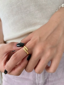 Close-up of minimalist gold geometric open ring with overlapping metal bars on finger